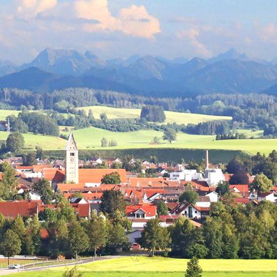 Blick auf das malerisches Obergünzburg im Allgäu umgeben von grünen Wiesen und Bergen im Hintergrund. Standort von SDLK Engineering GmbH